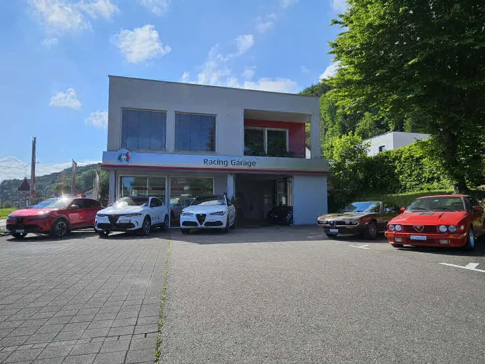 A red Alfa Romeo Tonale SUV displayed outside the Racing Garage Nägele showroom.