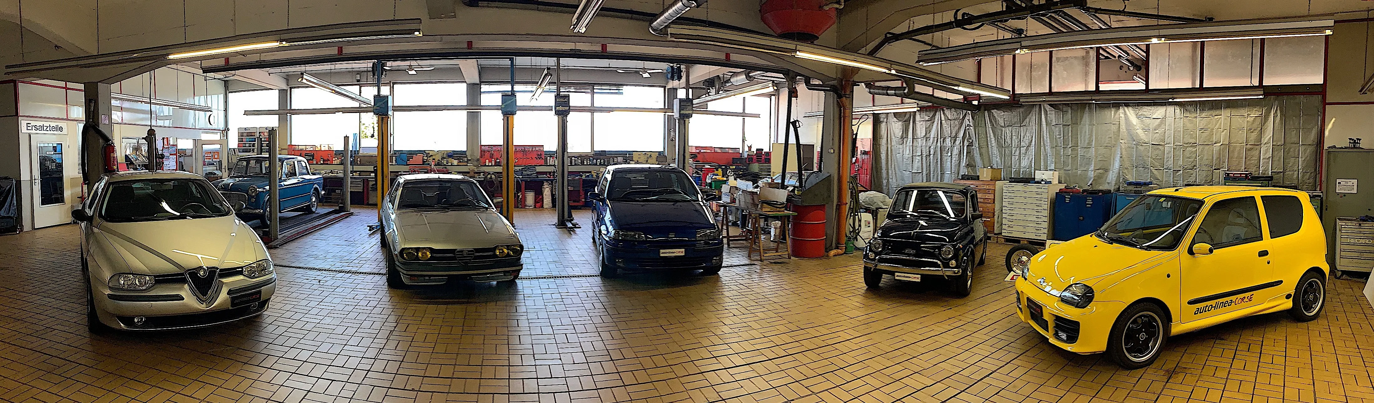 Two mechanics in uniform give thumbs up holding wrench and car key in a professional garage.