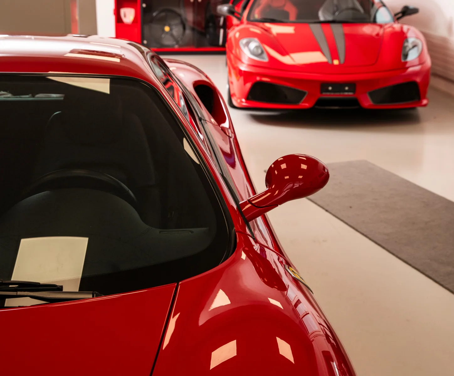 A focused mechanic works underneath a lifted Ferrari on a hydraulic lift, embodying the expert craftsmanship at the heart of Sportgarage Leirer AG.