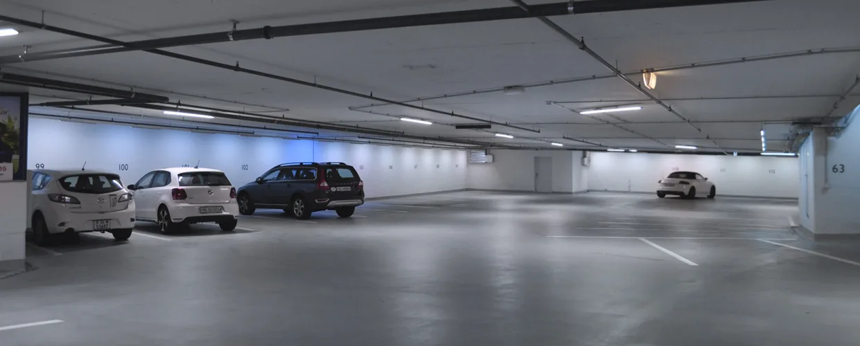 Spacious underground parking garage with numbered bays and several cars parked inside.