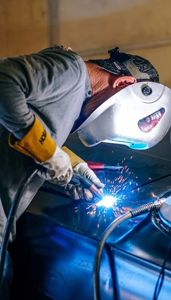 Welder creating sparks on metal — represents the skilled industrial craftsmanship and manufacturing quality associated with German filter engineering tradition.